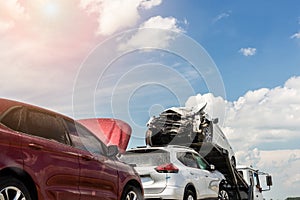 Tow truck trailer on highway carrying three damaged cars sold on insurance car auctions for repair and recovery.  Vehicles