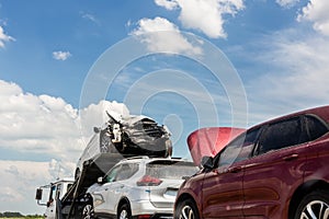 Tow truck trailer on highway carrying three damaged cars sold on insurance car auctions for repair and recovery.  Vehicles photo