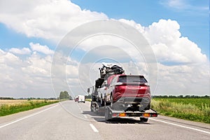 Tow truck trailer on highway carrying three damaged cars sold on insurance car auctions for repair and recovery.  Vehicles