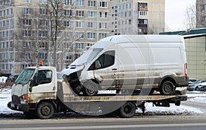 A tow truck transports a broken white minibus for repair photo