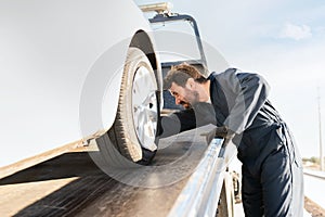 Tow truck worker securing the car on the platform