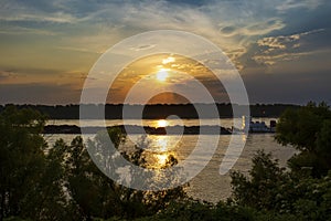 A towboat with barges in the Mississippi river at sunset near the city of Vicksburg in the State of Mississipp