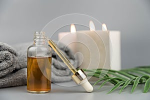 Towel with aromatic candles and bottle with natural organic oil essence serum.