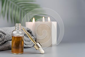 Towel with aromatic candles and bottle with natural organic oil essence serum.