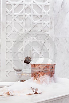 Towel and copper bowl with soap foam in turkish hamam. Tradition