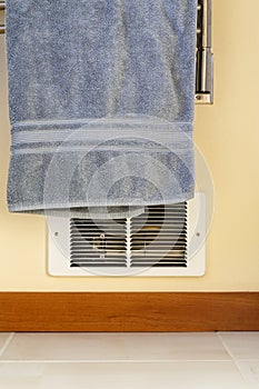 Towel hanging in front of in-wall electric baseboard heater heating unit. Dangerous house home fire hazards.