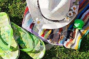 Towel, hat, sunglasses and chamomile on grass