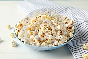Towel and plate with popcorn on white wood background