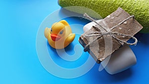 Towel, soap and yellow toy duck on a blue background. Flat lay photo, top view