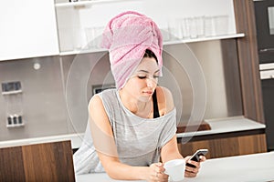 Towel-wrapped hair, young woman, smartphone, waiting, bright kit photo