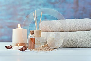 Towels, candle and massage oil on white table