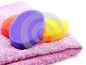 Towels with colorful pieces of soap isolated on white background