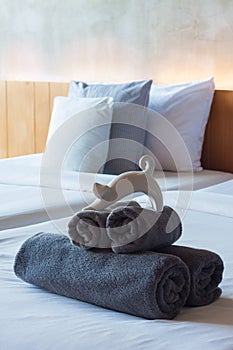 Towels roll on bed with ceramic cat.