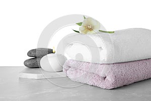 Towels, spa stones and flower on table against white background