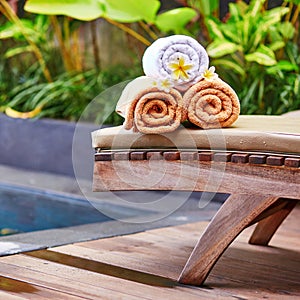 Towels with white frangipani flowers near the pool