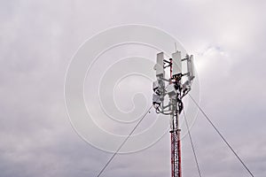 Tower with 5G and 4G cellular network antenna on grey cloudy sky background