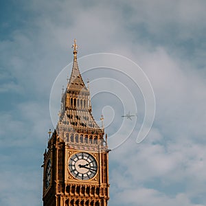 a tower is against a cloudy blue sky, with a plane flying above
