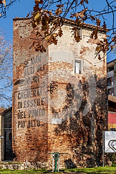 The tower of the ancient city walls of Cascina, Pisa, Italy, with the italian exhortation to look higher