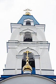 The tower with the bell of the Christian Church with blue domes and gold crosses.