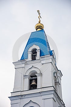 The tower with the bell of the Christian Church with blue domes and gold crosses.