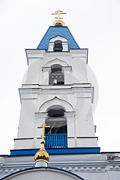 The tower with the bell of the Christian Church with blue domes and gold crosses.