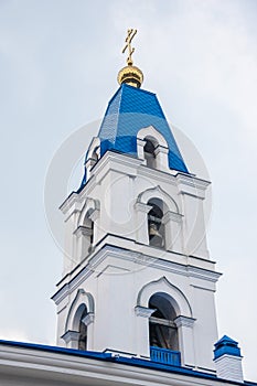 The tower with the bell of the Christian Church with blue domes and gold crosses.