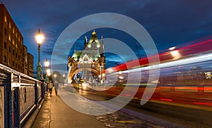 Tower bridge and red bus speed at night in London, UK