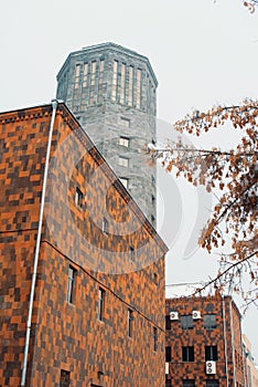 A tower and a building made of red, brown and black tuff stones,