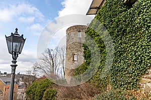 Tower of castle Muenstereifel, wall covered with ivy and street lamp