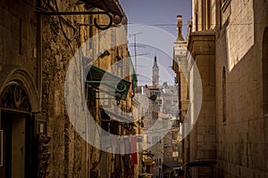 The tower of the Christian church is seen through the narrow street alley in Old Town of Jerusalem.