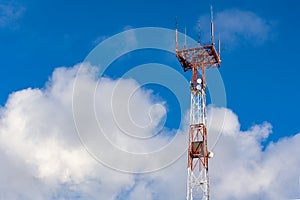 Tower connection with the mast and antennas against the blue sky with clouds. Transmission and reception of signals.