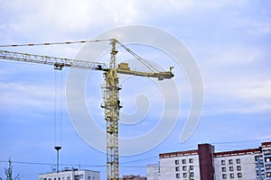 Tower construction crane on the background of the blue sky and the city