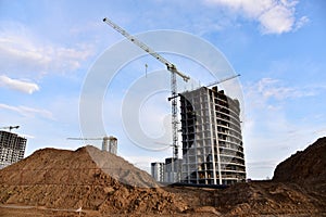 Tower crane in action at construction site on blue sky background. Crane the build the high-rise building. New residential