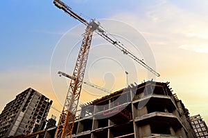 Tower crane in action at construction site on blue sky background. Crane the build the high-rise building. New residential