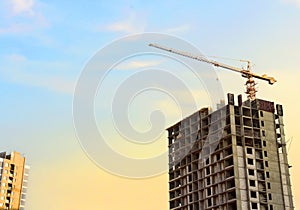 Tower crane in action at construction site on blue sky background. Crane the build the high-rise building. New residential