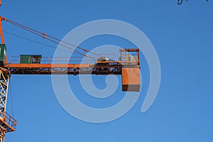 Tower crane against blue sky on a construction site for building of multi storage building or another type of structure.