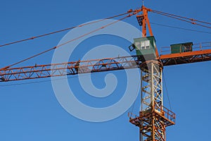 Tower crane against blue sky on a construction site for building of multi storage building or another type of structure.