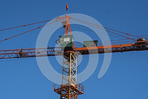 Tower crane against blue sky on a construction site for building of multi storage building or another type of structure.