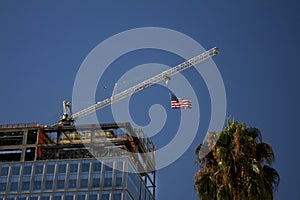 Tower Crane with an American flag near a modern office building under construction