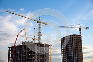 Tower crane and builders in action on blue sky background. Workers during formwork and pouring concrete through a Ñoncrete pump