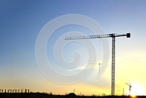 Tower crane constructing a new building at a construction site at sunset background.