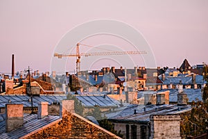 Tower crane on construction site on blue sky background and cityscape. City skyline in morning sunlight. Selective focus