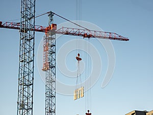 Tower crane delivers a concrete slab at a construction site. Construction of panel high-rise buildings