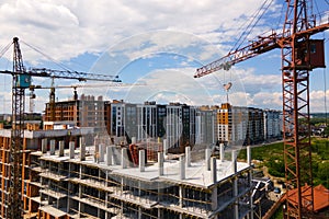 Tower crane at high concrete residential building under construction. Real estate development concept