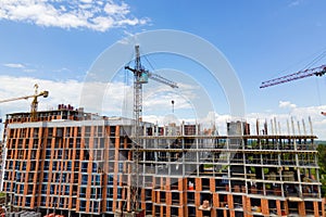 Tower crane at high concrete residential building under construction. Real estate development concept