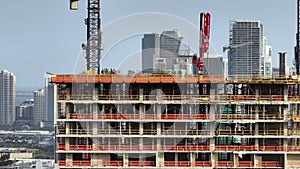 Tower crane at high residential apartment building construction site. Real estate development in Miami urban area