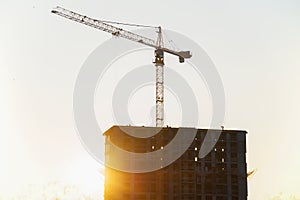 Tower crane lifting concrete bucket for pouring concrete during construction new residential building on blue sky background