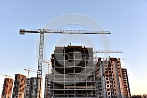 Tower crane lifting concrete bucket for pouring concrete during construction new residential building on blue sky background.