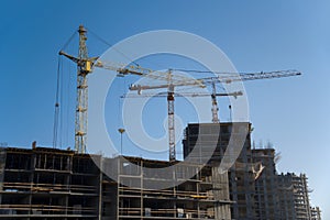 Tower crane lifting concrete bucket for pouring concrete during construction residential building on blue sky background