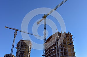 Tower crane lifting concrete bucket for pouring concrete during construction residential building on blue sky background. Builder